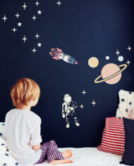 cute kid in pajamas dreaming , while sitting in bed and looking on chalkboard wall